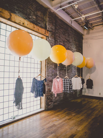 Pastel balloon installation with hanging garments.