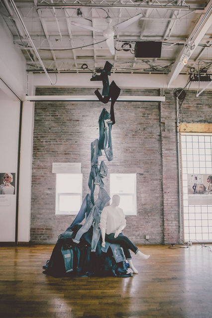 Towering denim fabric sculpture in an industrial gallery space.