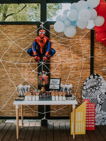 Spider-Man themed birthday party backdrop with balloon arch and spiderweb details.