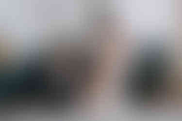 A woman in navy bends over to attach her friend's bridal shoe