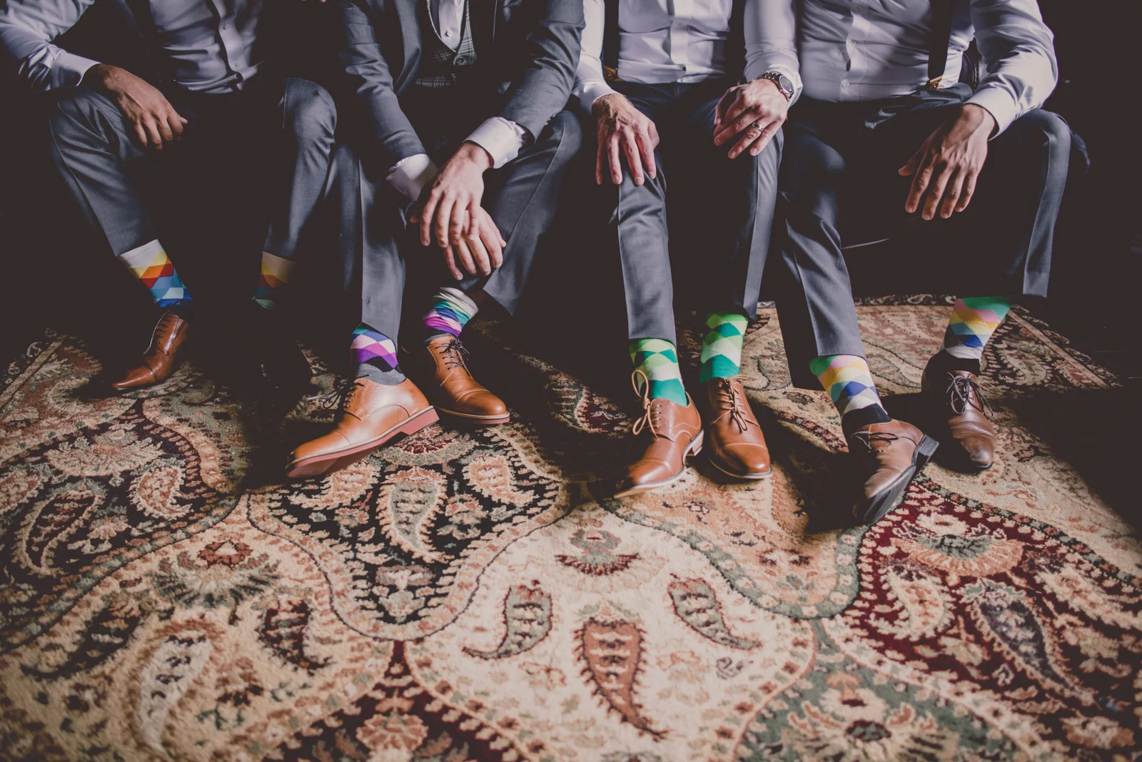 a close up of mens legs, showing off brown dress shoes and colourful socks