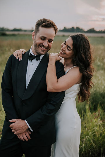 Bride and groom embracing in a rustic field during their Brighthouse Farm wedding
