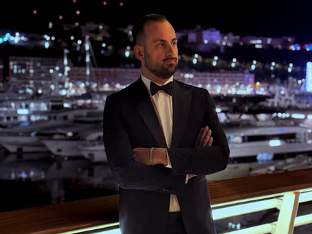 Andrea Battista, Head of Legal at CGPH Banque d’Affaires, pictured at the Monaco Yacht Club during the Christmas Gala of the Monte-Carlo Ambassador Club, overlooking Port Hercules at night.