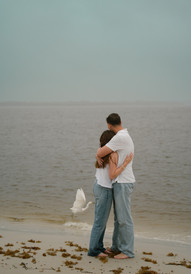 Man and woman hugging on the beach as a bird flies away in Smyrna Dunes Park