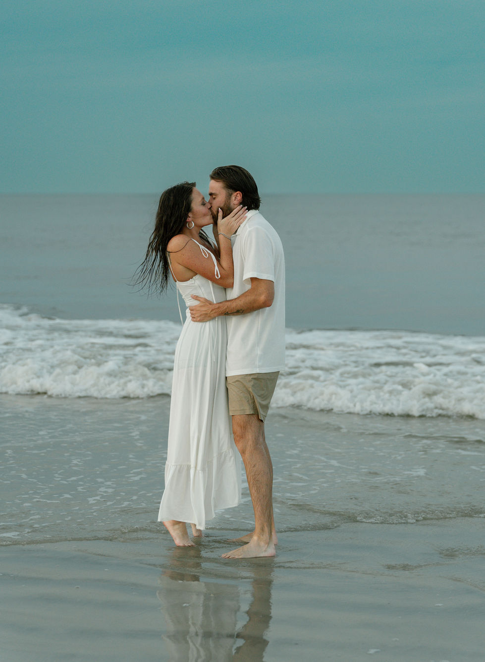 Couple embracing on a beach at sunset.