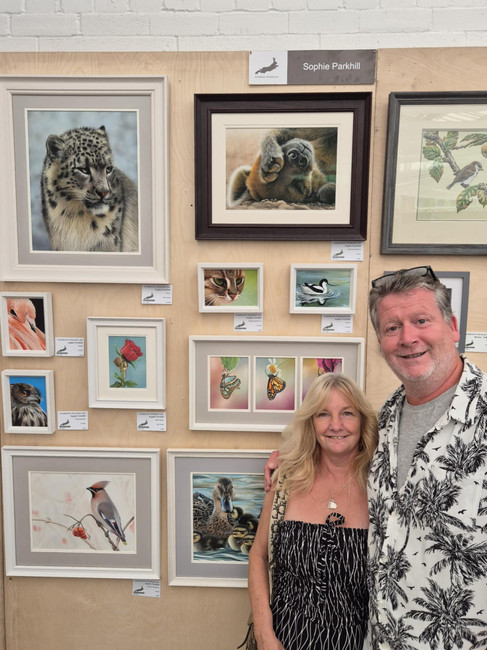 The parents of artist Sophie Parkhill at her display for Exhibition Wildlife Art 2025