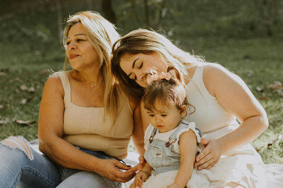 A Latina mother and daughter smiling warmly at a young child in a garden, capturing a tender moment of family connection and support.