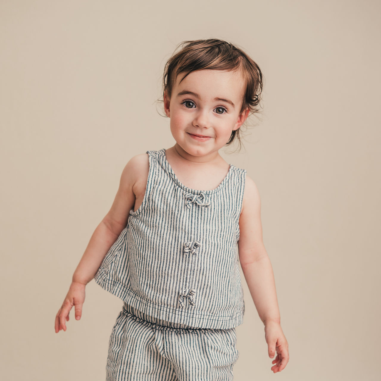Young child standing with a quiet smile during a fine art school portrait