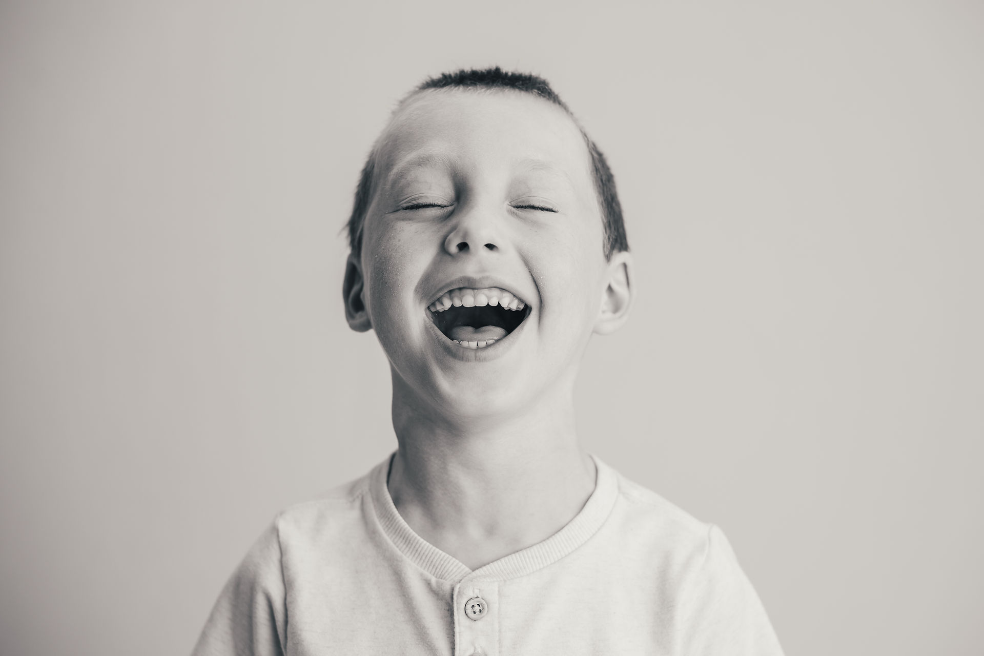 Black and white school portrait of a boy laughing with his eyes closed