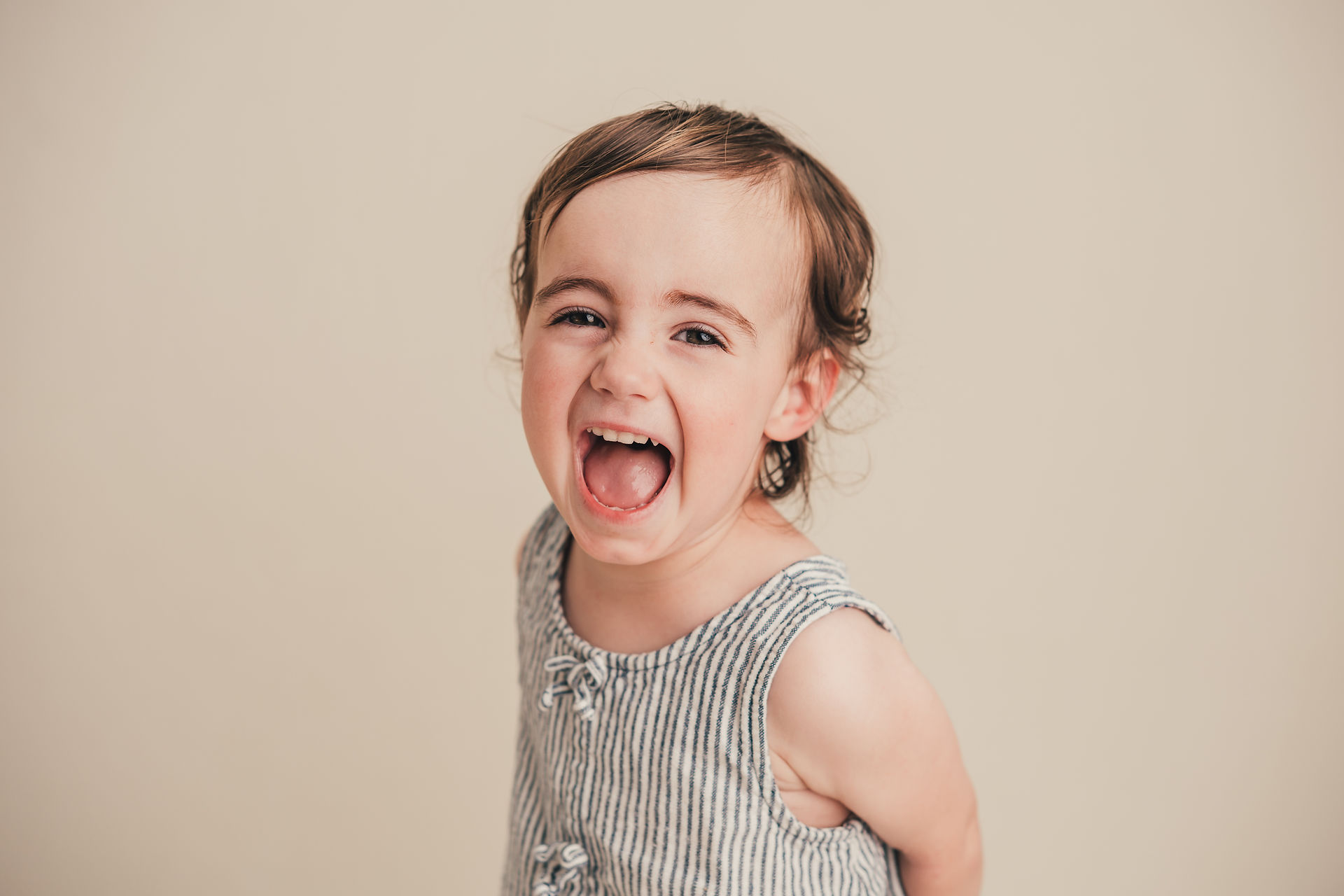 Young child laughing with an open-mouth smile during school pictures