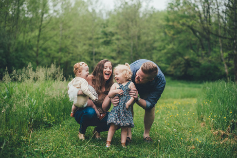Mom and Dad tickling their two little girls in a field of buttercups in Malvern, PA