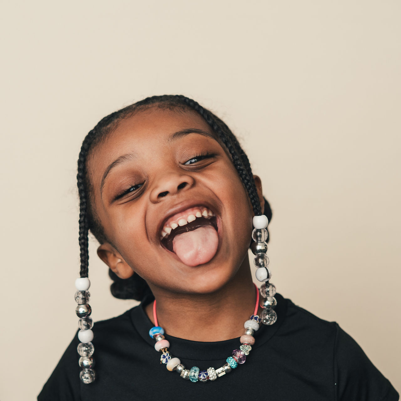 Girl with braids and beads laughing during a fine art school portrait