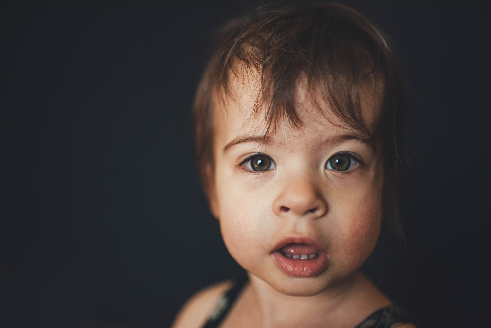 school portrait of toddler girl in front of black background