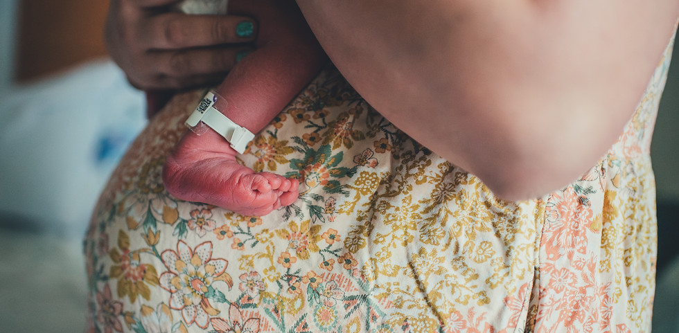 Belly of postpartum mom with newborn baby foot