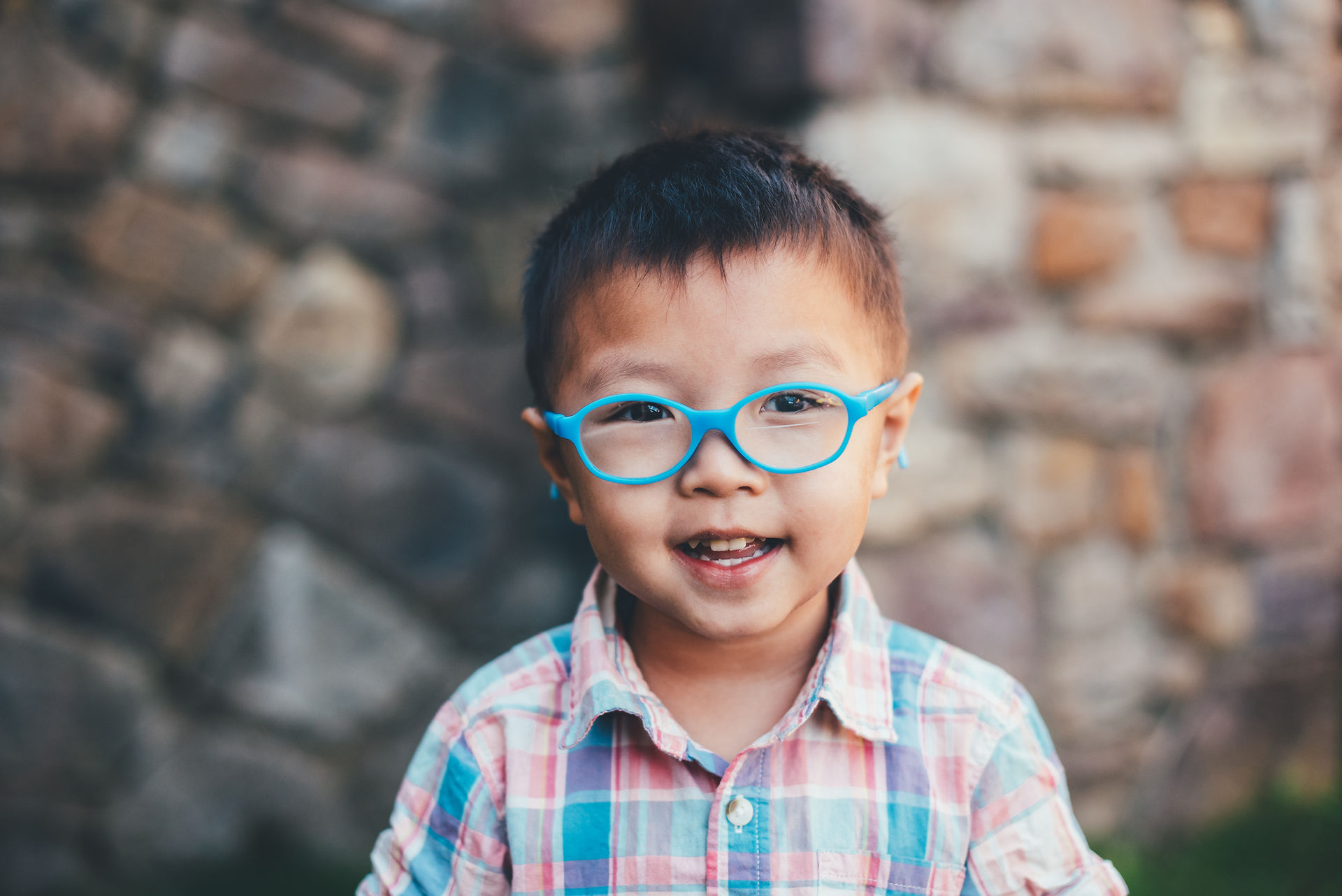 Boy with blue glasses wearing a colorful plaid shirt for outdoor school pictures