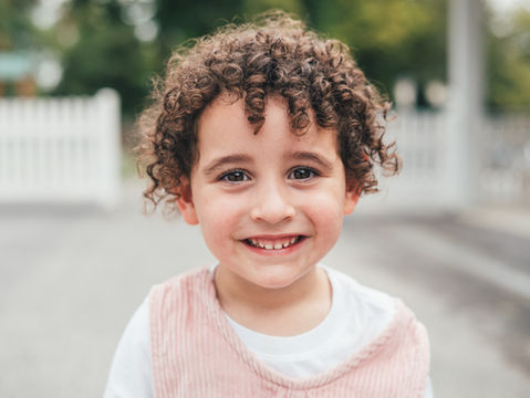 Young girl with curly hair smiling during an outdoor school portrait