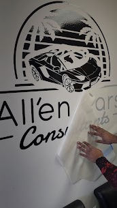 Hands peeling transfer tape from a large black vinyl wall decal featuring the All’en Cars logo with a sports car and palm trees design.