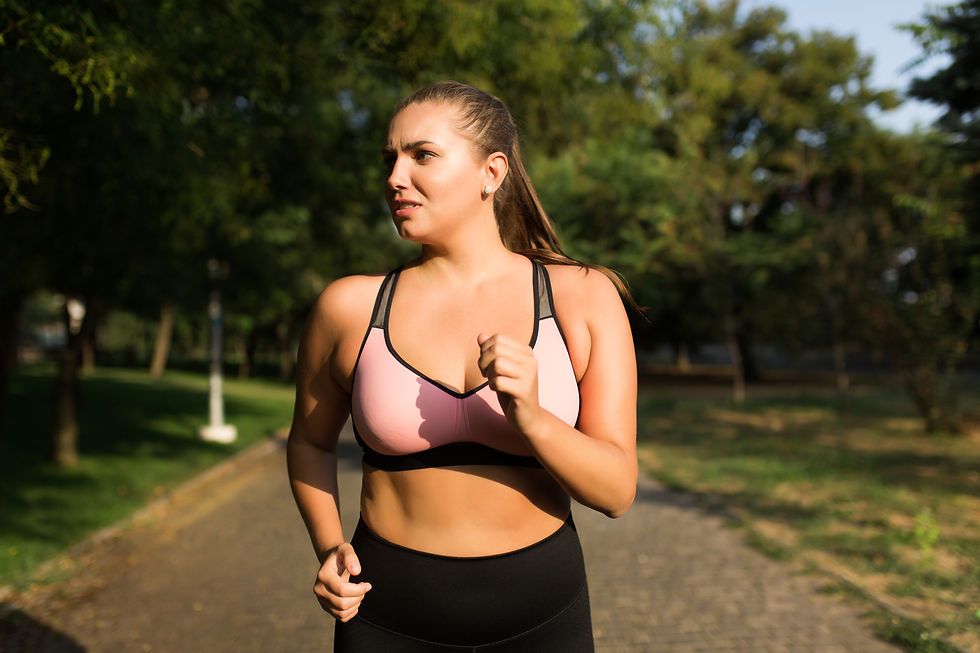 Woman jogging on a park path in pink-and-black sportswear, looking focused with green trees blurred behind her.