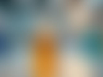 A small bottle of guaifenesin with amber liquid on a lab bench, illuminated by fluorescent lights. Blurred lab equipment in the background.