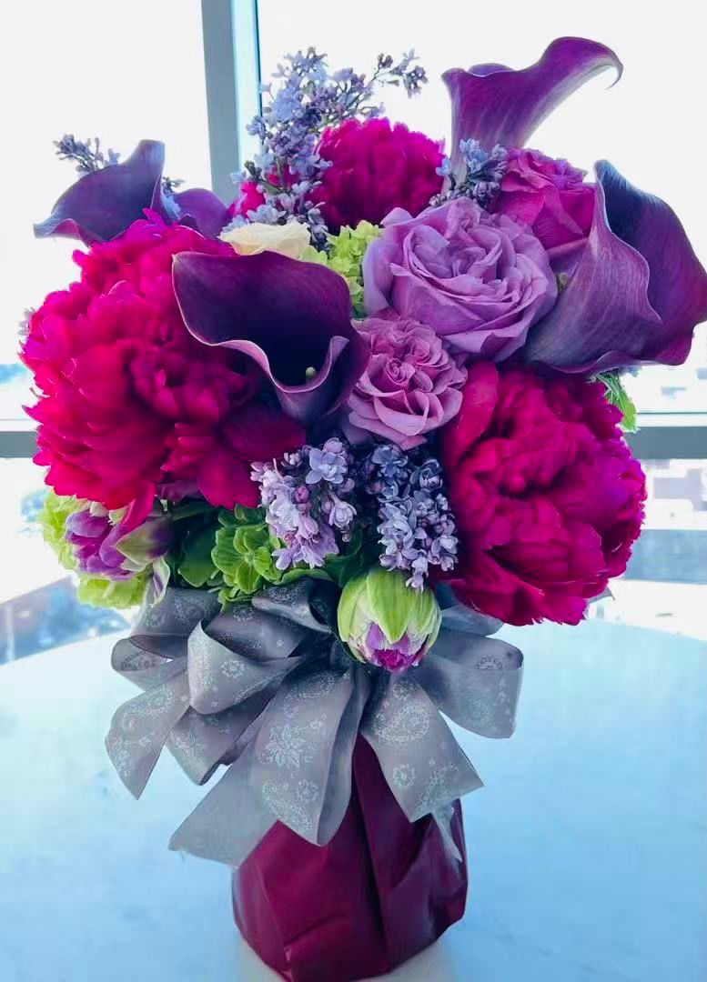 Bright pink and purple floral arrangement in a vase, portrait photo