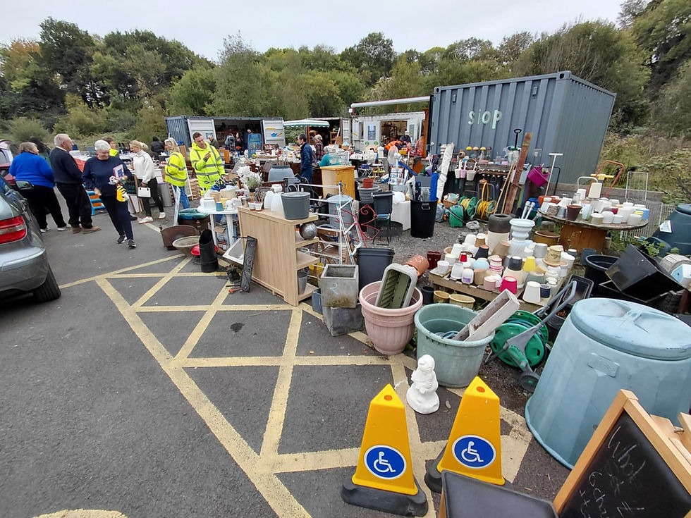 Monmouthshire reuse shop yard with accessible parking cones in foreground and crowds browsing preloved garden and home items.
