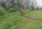 Hiker with a straw hat, red backpack, and hiking staff taking the path on the left.