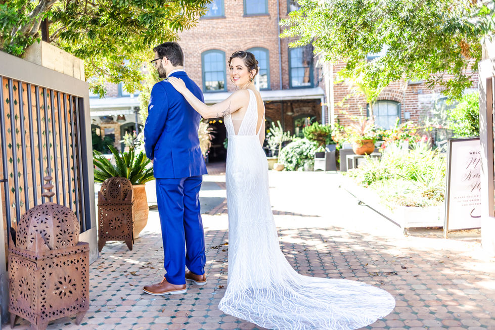 a bride in a white dress is standing next to a groom in a blue suit