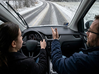 light snow on the road from POV of inside a car while someone is teaching the driver how t