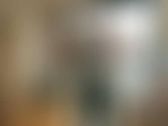 Ein junger, sportlicher Schwarzer Mann startet voller Energie und mit einem breiten Lächeln in den Tag. Er steht in einer hellen, modern eingerichteten Dachgeschosswohnung und streckt motiviert die Arme nach oben. Er trägt graue Sportkleidung; im Vordergrund auf einer Küchentheke steht ein gesundes Frühstück mit Müsli, Obst und Orangensaft. Durch das große Panoramafenster im Hintergrund ist die Skyline von Köln mit dem markanten Dom im warmen Licht der Morgensonne zu sehen. Die Atmosphäre ist inspirierend, vital und optimistisch.