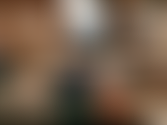 Eine surreale Szene in einem modernen Loft-Büro einer Kreativagentur während der Abendstunden. Im Vordergrund schläft eine stilvoll gekleidete Frau friedlich in einem gemütlich ausgestatteten Bett mit grüner Decke und Terrakotta-Kissen, das mitten im Raum steht. Auf einem der Kissen ist das Logo „Bold Minds“ zu sehen. Auf dem Nachttisch neben ihr liegt ein Notizblock mit der Aufschrift „LEAVE ME BE“. Im Hintergrund arbeiten ihre Kollegen konzentriert an Schreibtischen vor einer unverputzten Backsteinwand mit Moodboards, während durch die großen Fenster die Lichter der Stadt bei Dämmerung zu sehen sind. Die warme Beleuchtung und die Lichterketten verleihen der Szene eine ruhige, fast traumartige Atmosphäre.