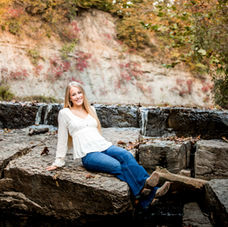 Missouri high school senior sitting on rocks at a waterfall for portrait photographer, Carrie Watson.