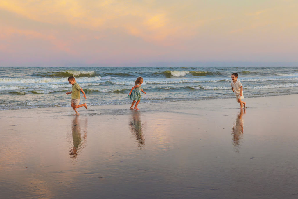Family walking along the shoreline in Stone Harbor NJ for a natural, lifestyle beach photography session.