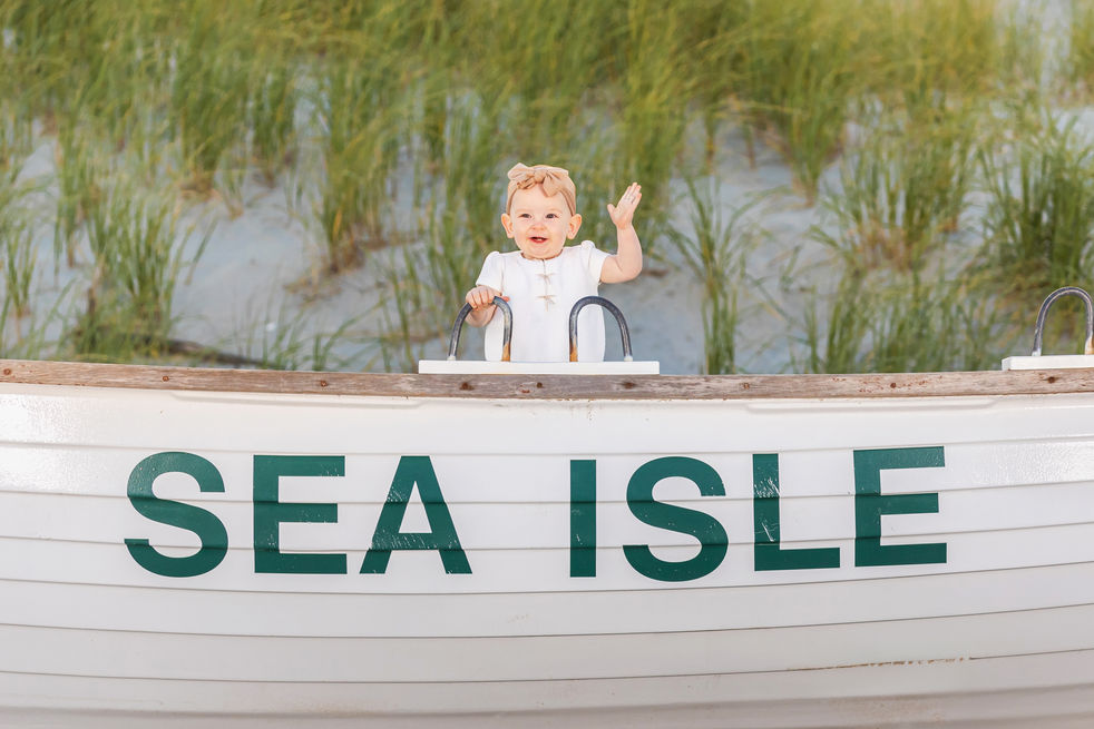 Candid photography of siblings laughing on the sand in Sea Isle City NJ during a summer beach session.featuring the lifeguard boat and coastal scenery.