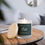 Thumbnail: Oakmoss 11oz Candle - Candle on a table, lit, with the lid off and leaning on the candle