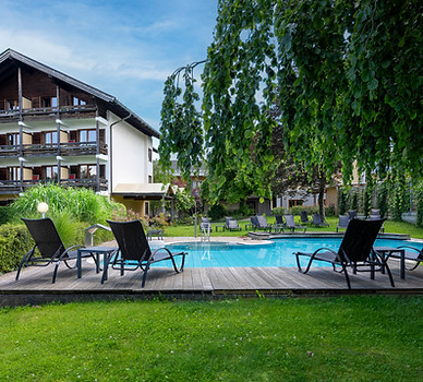 Hotelpool mit Liegestühlen und Garten