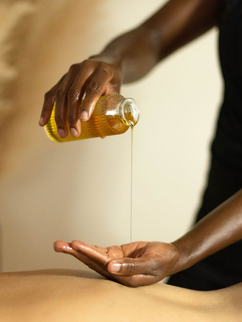 Femme noir versant de l'huile des massage dans sa main. Envoie à la page du massage suédois.