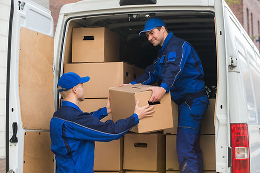 Two removal workers loading cardboard boxes into back of van