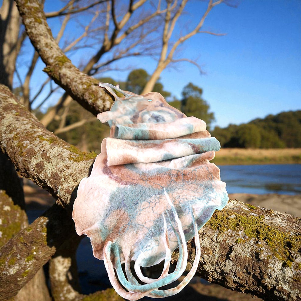 Cream, pale blue and fawn alpaca felt wrap draped over a fallen tree branch.