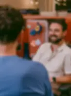 Gülümseyen adam, iş arkadaşıyla ofiste konuşuyor