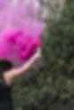Founder of Designed To See holding a pink smoke flare in a forest, representing embodied business consulting and creative workplace wellbeing.