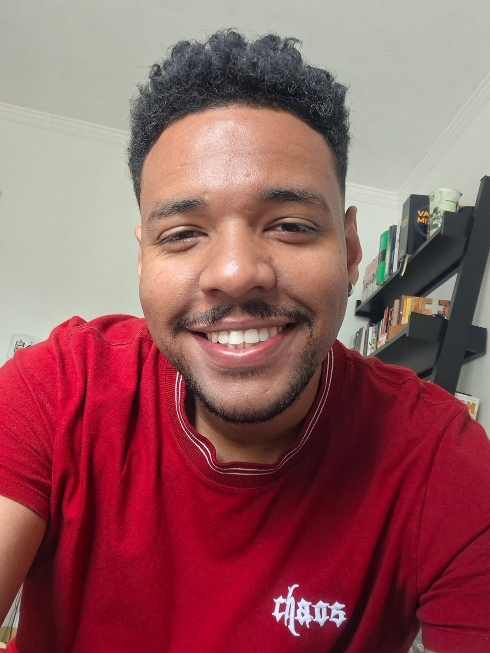 Homem de pele marrom clara, cabelos e olhos escuros, usando uma camiseta vermelha