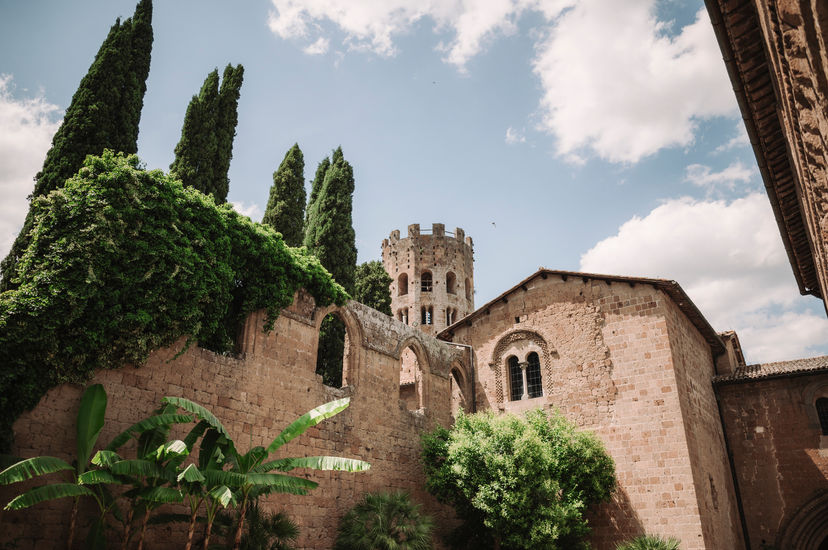 Stone buildings with tower and trees under a cloudy sky. riccardopieri