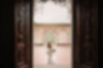 Bride walking through an ancient doorway, framed by historic architecture and soft natural light, elegant and serene atmosphere in Italy