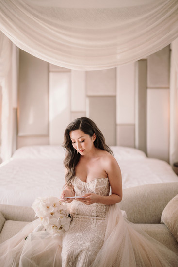 Bride reading a letter, wearing a white wedding dress in a room