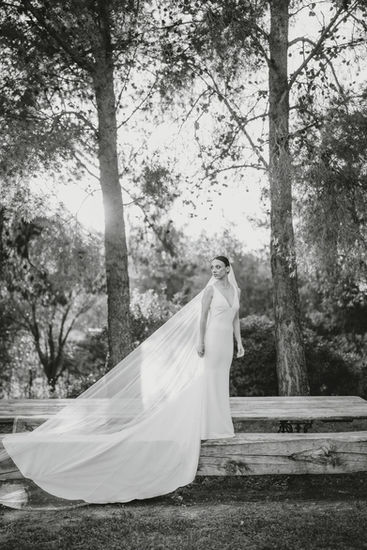 Bride in wedding dress posing, veil flowing; seaside wedding at Borgo dei Santi.