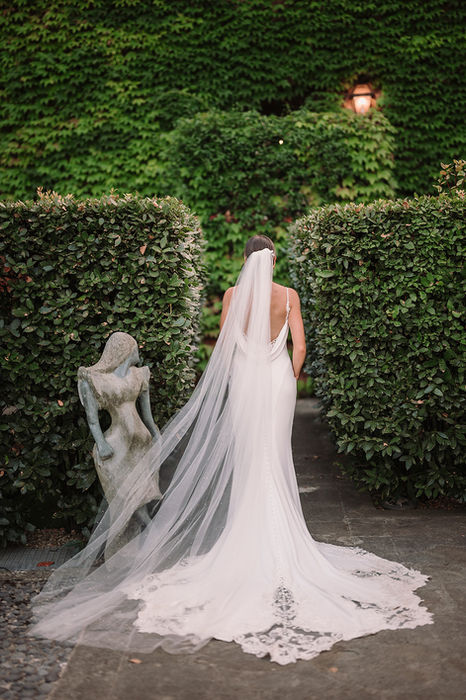 Bride with long veil walking in the garden at Villa Mangiacane wedding in Tuscany