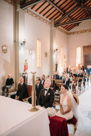 Sposa e sposo seduti in chiesa durante la cerimonia nuziale con invitati.