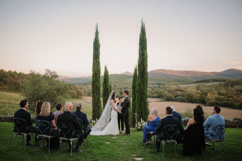 Intimate outdoor wedding ceremony at Borgo Santo Pietro framed by cypress trees and Tuscan hills