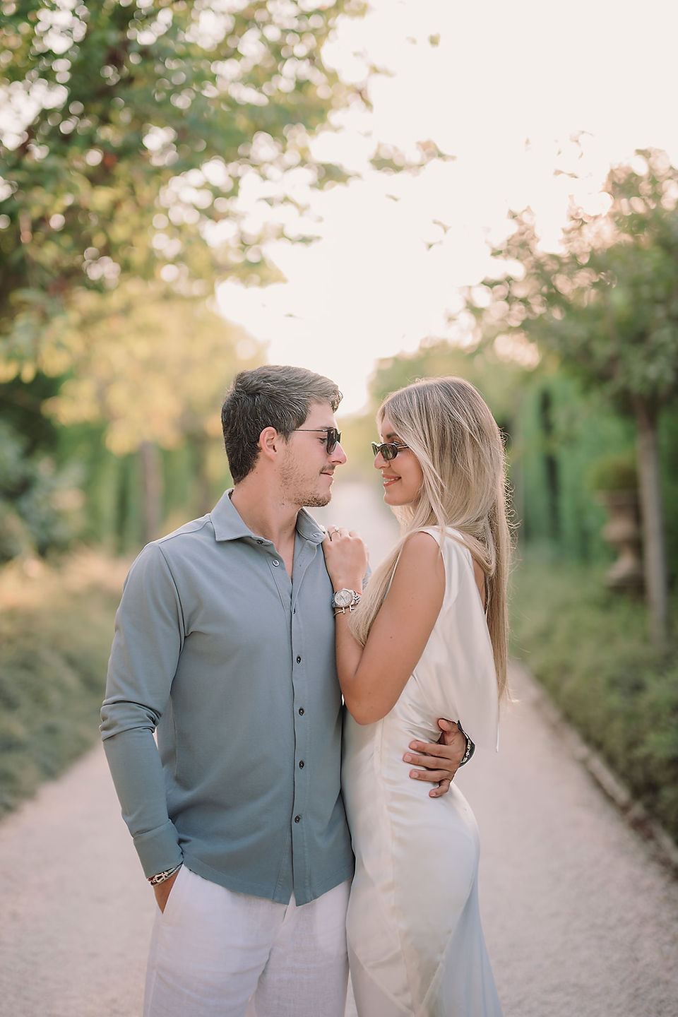 Couple sharing an intimate moment on a sunlit garden path in Tuscany, relaxed and romantic atmosphere with soft natural light