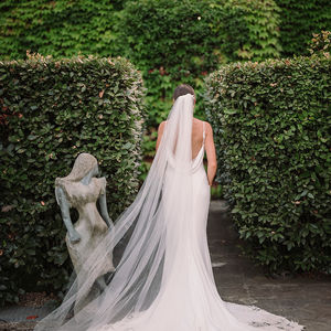 Bride viewed from the back, walking on a stone path, showing the scoop back dress.